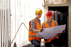 two Engineers reading a blue print in a construction floor for the page How To Perfect Your Civil Engineering Resume